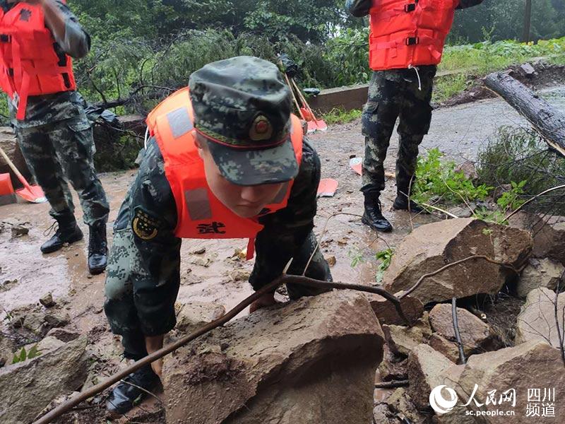 武警官兵前往营山县双流镇途中路遇落石,救援官兵搬运石头,清理障碍