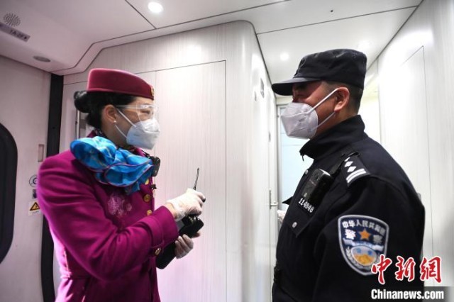 张金玉(右)与列车长进行交流信息。 安源 摄